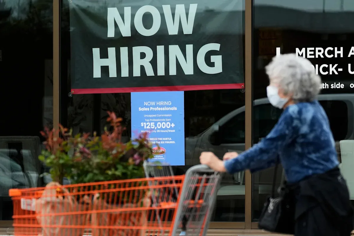 A hiring sign outside a business as labor market data shows steady openings and hiring